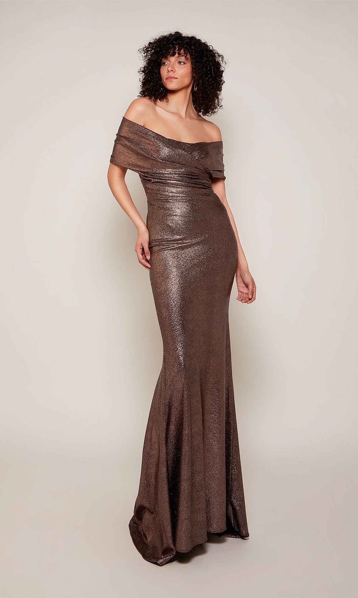 A person wears the Alyce 27666 long formal cocoa dress, a metallic off-the-shoulder mother-of-the-bride evening gown, standing against a plain light background.